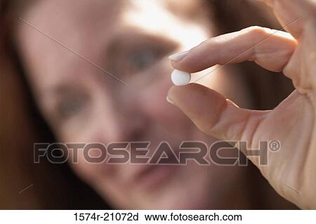 Stock Image - Close-up of a mature woman showing a pill. Fotosearch