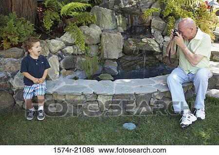 Mature man taking a photograph of his grandson View Large Photo Image Stock Photography - Mature man taking a photograph of his grandson. Fotosearch