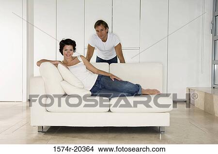 肖像画 の A 若い女性 よりかかる 上に A ソファー で A 若者 後ろ立つこと 彼女 ピクチャー 1574r 364 Fotosearch