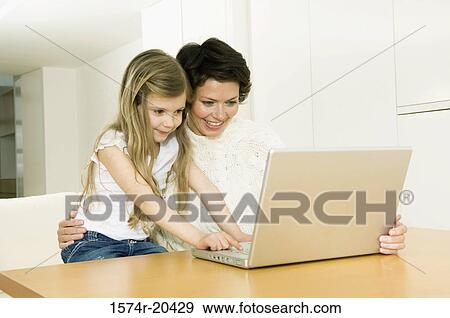 Close-up of a girl using a laptop with her mother View Large Photo Image Stock Photo - Close-up of a girl using a laptop with her mother. Fotosearch