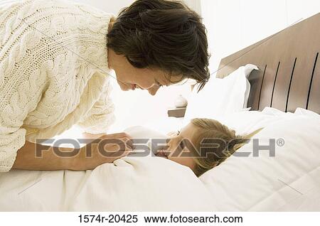 Close-up of a mother bending over her daughter lying on the bed View Large Photo Image Stock Photography - Close-up of a mother bending over her daughter lying on the bed. Fotosearch