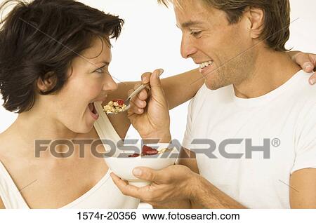 Close-up of a young man feeding a young woman View Large Photo Image Stock Photograph - Close-up of a young man feeding a young woman. Fotosearch