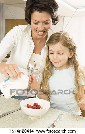 Close-up of a young woman serving breakfast to her daughter View Large Photo Image Picture - Close-up of a young woman serving breakfast to her daughter. Fotosearch