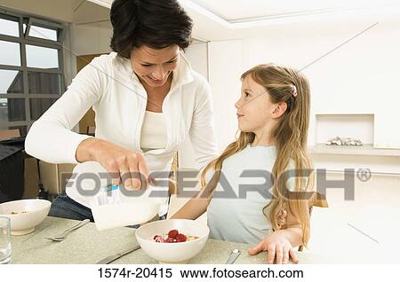Close-up of a young woman serving breakfast to her daughter View Large Photo Image Stock Photography - Close-up of a young woman serving breakfast to her daughter. Fotosearch
