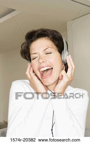 Close-up of a young woman wearing headphones and listening to music View Large Photo Image Stock Image - Close-up of a young woman wearing headphones and listening to music. Fotosearch