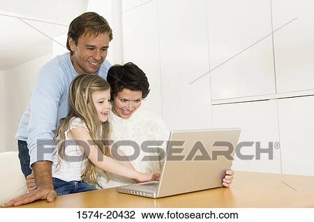 Girl using a laptop with her parents View Large Photo Image Stock Image - Girl using a laptop with her parents. Fotosearch
