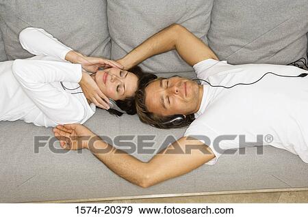 High angle view of a young couple listening to music on a couch View Large Photo Image Stock Photo - High angle view of a young couple listening to music on a couch. Fotosearch