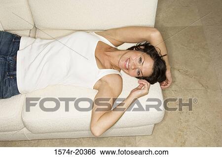 High angle view of a young woman lying on a couch and smiling View Large Photo Image Stock Photograph - High angle view of a young woman lying on a couch and smiling. Fotosearch