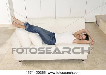 High angle view of a young woman lying on a couch and smiling View Large Photo Image Stock Photography - High angle view of a young woman lying on a couch and smiling. Fotosearch
