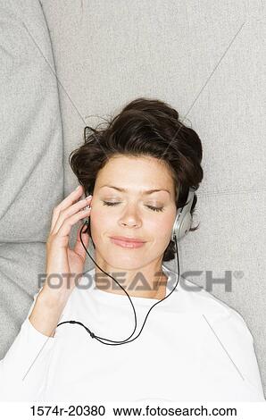 High angle view of a young woman wearing headphones and listening to music View Large Photo Image Stock Image - High angle view of a young woman wearing headphones and listening to music. Fotosearch
