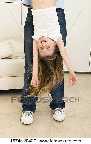 Stock Photo - Low section view of a young man holding his daughter upside down. Fotosearch