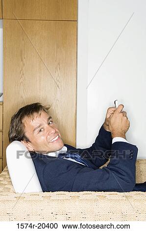 Portrait of a businessman sitting in an armchair and holding a mobile phone View Large Photo Image Stock Image - Portrait of a businessman sitting in an armchair and holding a mobile phone. Fotosearch