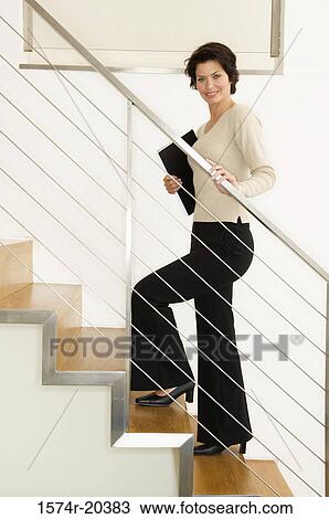 Stock Image - Portrait of a businesswoman climbing up stairs. Fotosearch