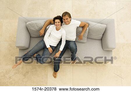 Portrait of a young couple sitting on a couch and smiling View Large Photo Image Stock Photo - Portrait of a young couple sitting on a couch and smiling. Fotosearch
