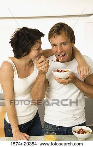 Portrait of a young man eating fruit salad with a young woman looking at him View Large Photo Image Picture - Portrait of a young man eating fruit salad with a young woman looking at him. Fotosearch