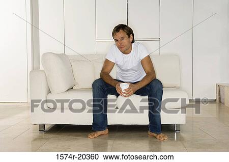 Portrait of a young man sitting on a couch View Large Photo Image Stock Image - Portrait of a young man sitting on a couch. Fotosearch