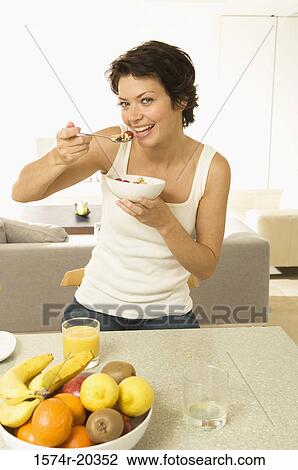 Stock Image - Portrait of a young woman eating fruit salad. Fotosearch