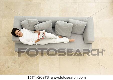 Portrait of a young woman lying on a couch View Large Photo Image Stock Photograph - Portrait of a young woman lying on a couch. Fotosearch