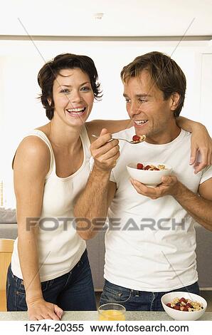Portrait of a young woman smiling with a young man eating fruit salad beside her View Large Photo Image Stock Photography - Portrait of a young woman smiling with a young man eating fruit salad beside her. Fotosearch