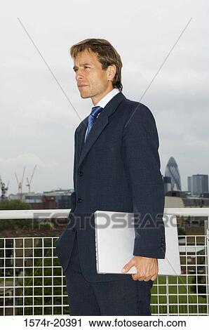 Side profile of a businessman holding a laptop View Large Photo Image Stock Image - Side profile of a businessman holding a laptop. Fotosearch