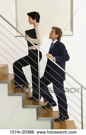 Side profile of a businesswoman climbing up stairs with a businessman View Large Photo Image Stock Photo - Side profile of a businesswoman climbing up stairs with a businessman. Fotosearch