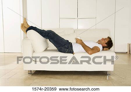 Side profile of a young man lying on a couch View Large Photo Image Stock Photo - Side profile of a young man lying on a couch. Fotosearch