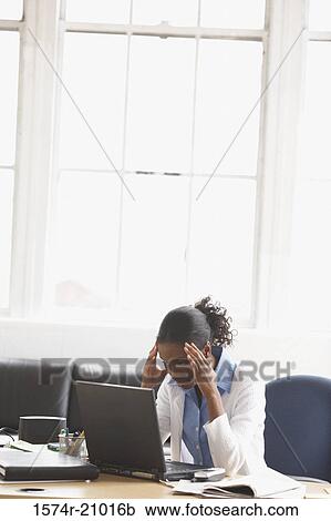 Businesswoman sitting in an office with her hands on her forehead View Large Photo Image Stock Image - Businesswoman sitting in an office with her hands on her forehead. Fotosearch