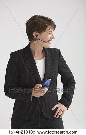 Stock Image - Close-up of a businesswoman talking on a mobile phone using a hands free device. Fotosearch