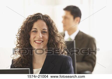 Portrait of a businesswoman smiling with a businessman in the background View Large Photo Image Picture - Portrait of a businesswoman smiling with a businessman in the background. Fotosearch
