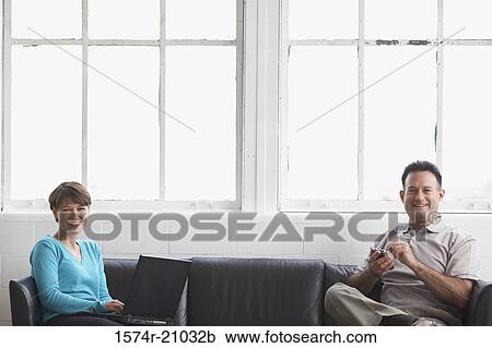 Portrait of a businesswoman working on a laptop with a businessman using a PDA View Large Photo Image Stock Image - Portrait of a businesswoman working on a laptop with a businessman using a PDA. Fotosearch