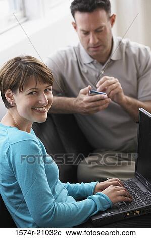 Portrait of a businesswoman working on a laptop with a businessman using a PDA View Large Photo Image Stock Image - Portrait of a businesswoman working on a laptop with a businessman using a PDA. Fotosearch