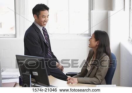Side profile of a businessman and a businesswoman talking to each other in an office View Large Photo Image Stock Photograph - Side profile of a businessman and a businesswoman talking to each other in an office. Fotosearch