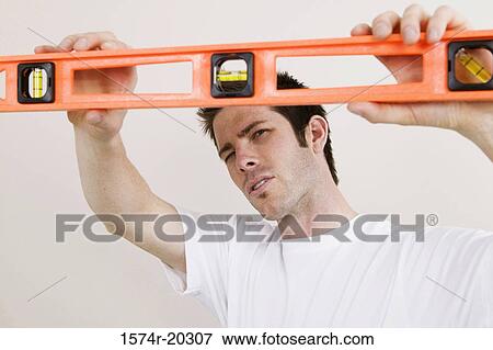 Close-up of a young man holding a spirit level View Large Photo Image Stock Photo - Close-up of a young man holding a spirit level. Fotosearch