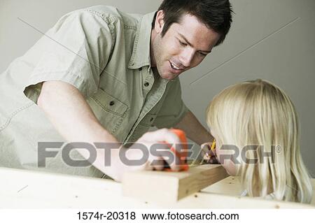 Stock Photo - Father holding a tape measure with his daughter marking on a plank with a pencil. Fotosearch