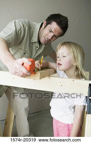 Father holding a tape measure with his daughter marking on a plank with a pencil View Large Photo Image Stock Photo - Father holding a tape measure with his daughter marking on a plank with a pencil. Fotosearch