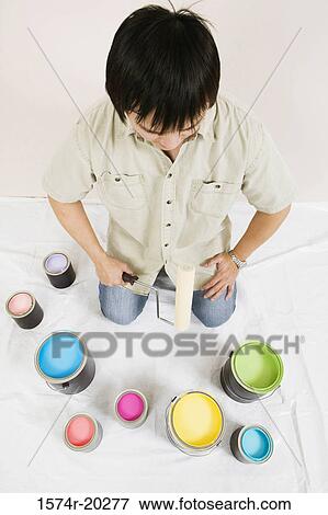 High angle view of a young man holding a paint roller with paint cans in front of him View Large Photo Image Stock Photo - High angle view of a young man holding a paint roller with paint cans in front of him. Fotosearch