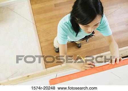 High angle view of a young woman using spirit level to mark on a wall View Large Photo Image Stock Photo - High angle view of a young woman using spirit level to mark on a wall. Fotosearch