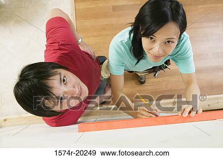 High angle view of a young woman using a spirit level to mark on a wall with a young man standing beside her View Large Photo Image Stock Photo - High angle view of a young woman using a spirit level to mark on a wall with a young man standing beside her. Fotosearch