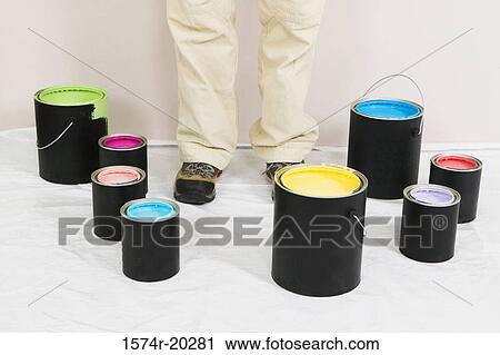 Stock Image - Low section view of a woman standing with paint cans around him. Fotosearch