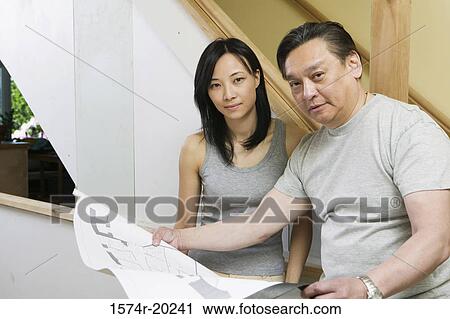 Portrait of a mid adult man holding a blueprint with a young woman beside him View Large Photo Image Stock Image - Portrait of a mid adult man holding a blueprint with a young woman beside him. Fotosearch