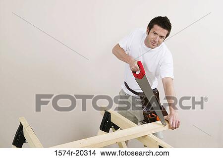 Portrait of a young man cutting a plank with a saw View Large Photo Image Picture - Portrait of a young man cutting a plank with a saw. Fotosearch