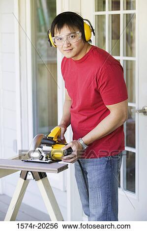 Portrait of a young man cutting a plank with an electric saw View Large Photo Image Stock Photograph - Portrait of a young man cutting a plank with an electric saw. Fotosearch
