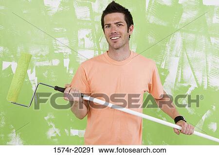 Portrait of a young man holding a paint roller View Large Photo Image Stock Image - Portrait of a young man holding a paint roller. Fotosearch