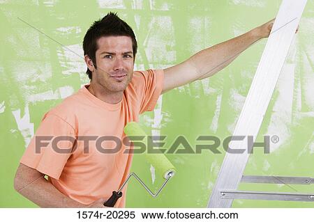 Portrait of a young man holding a paint roller View Large Photo Image Stock Photography - Portrait of a young man holding a paint roller. Fotosearch