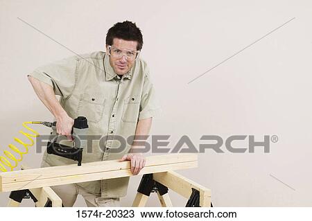Portrait of a young man nailing into a plank View Large Photo Image Stock Image - Portrait of a young man nailing into a plank. Fotosearch