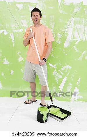 Portrait of a young man standing with a paint roller View Large Photo Image Stock Photo - Portrait of a young man standing with a paint roller. Fotosearch