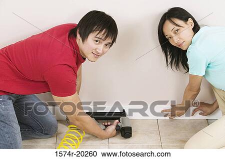 Portrait of a young man using a drill on a wall with a young woman helping him View Large Photo Image Stock Image - Portrait of a young man using a drill on a wall with a young woman helping him. Fotosearch