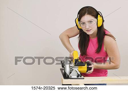 Portrait of a young woman cutting wood with an electric saw View Large Photo Image Stock Photography - Portrait of a young woman cutting wood with an electric saw. Fotosearch