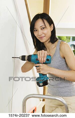 Portrait of a young woman drilling into a wall View Large Photo Image Stock Photo - Portrait of a young woman drilling into a wall. Fotosearch