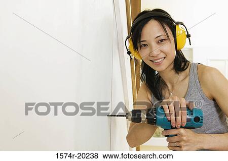 Portrait of a young woman drilling into a wall View Large Photo Image Stock Photo - Portrait of a young woman drilling into a wall. Fotosearch